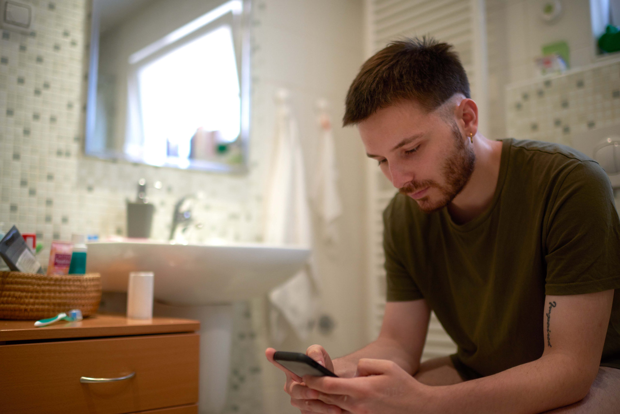 Man sits on toilet with phone