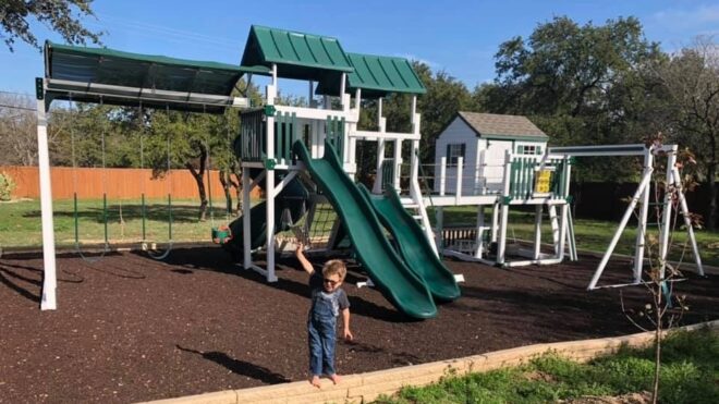 Colton Costa standing in front of the play set