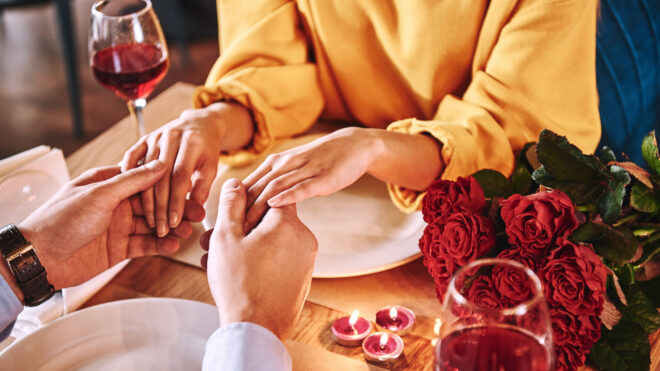 Romantic moments. Young man holding hands of his girlfriend in restaurant stock photo