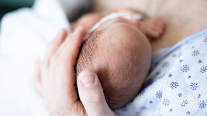 Newborn held by mother