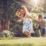kids running through sprinklers