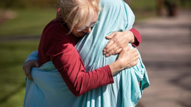 Mom hugs daughter through sheet