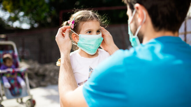 Dad putting face mask on little girl