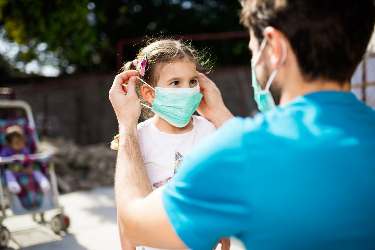 Dad putting face mask on little girl