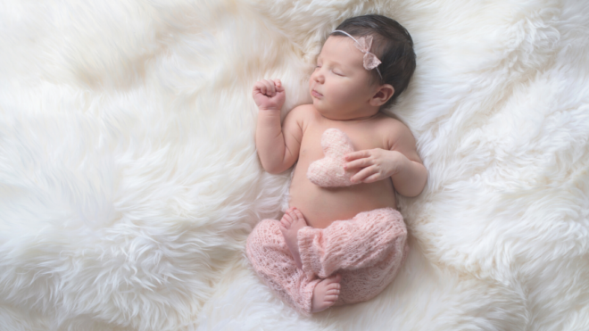 a baby girl sleeping on a white fuzzy blanket
