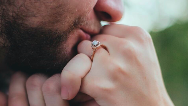 Man kissing hand with engagement ring