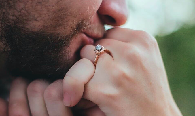 Man kissing hand with engagement ring