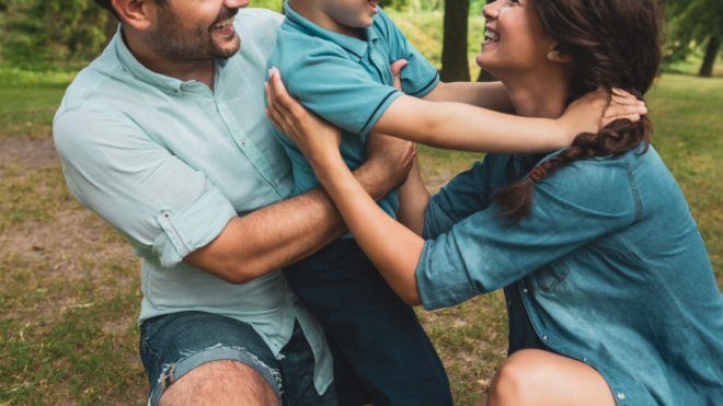 mom son and dad hugging at the park