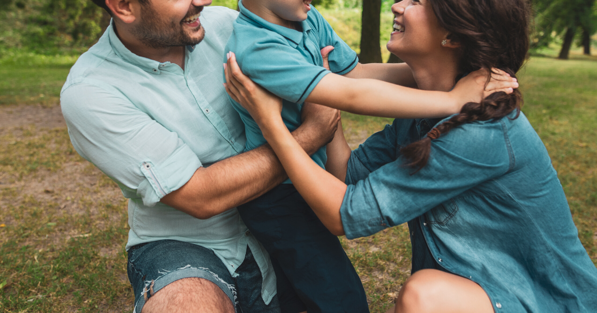 mom son and dad hugging at the park