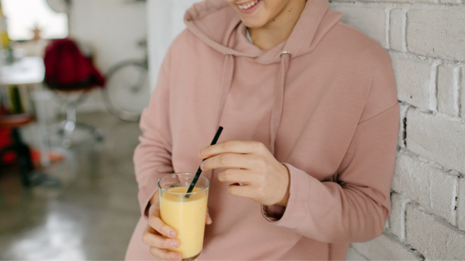 teen girl holding a smoothie in a glass