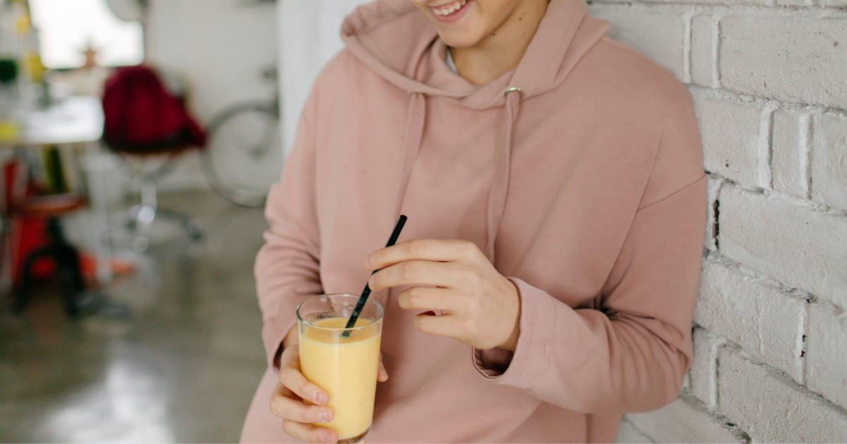 teen girl holding a smoothie in a glass
