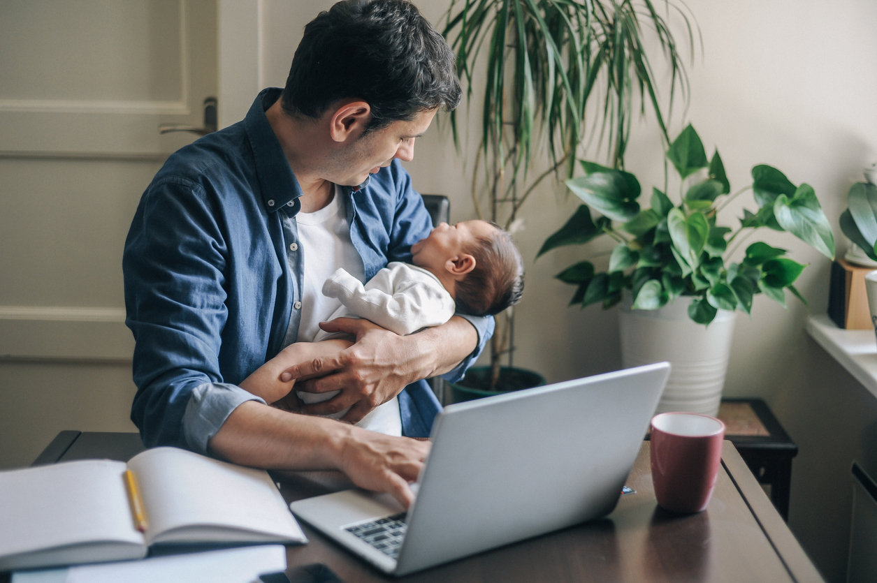 Dad working while holding newborn