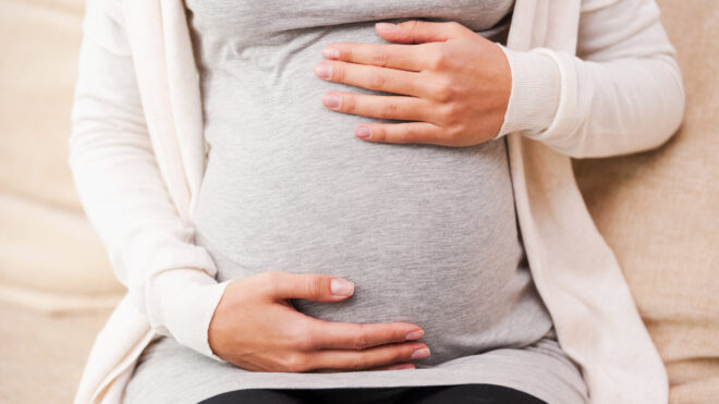 Pregnant woman holds belly