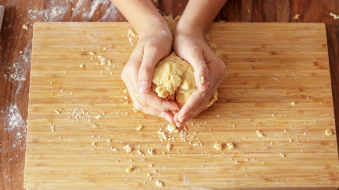 Top view of woman hands holding dough on wooden cutting board