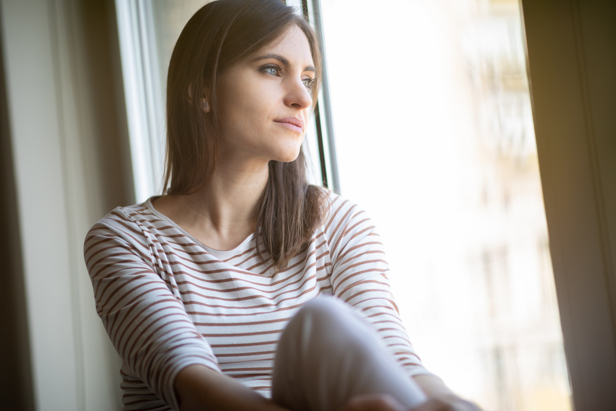 Woman seems serious while looking out window