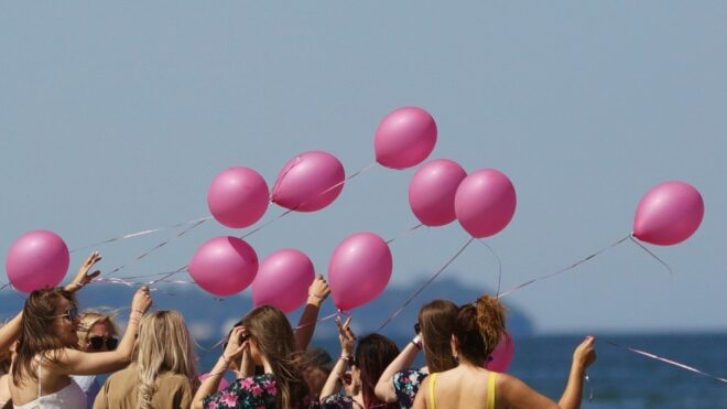 Friends holding pink balloons