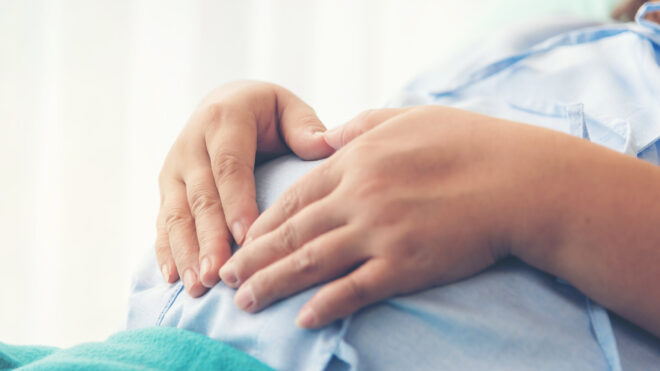 woman with hands on pregnant belly