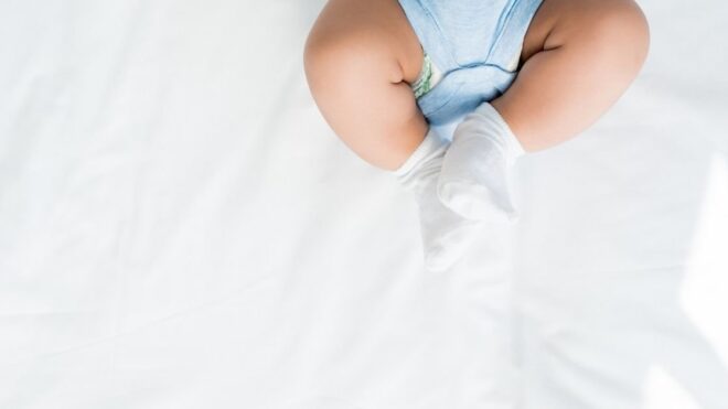 baby feet wearing socks and blue onesie on white background
