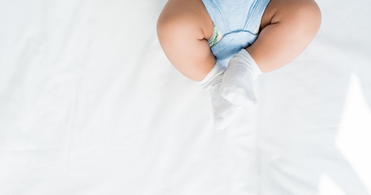 baby feet wearing socks and blue onesie on white background
