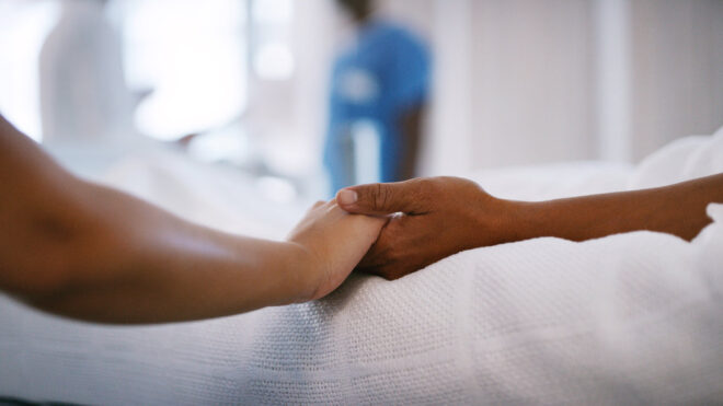 People holding hands from hospital bed