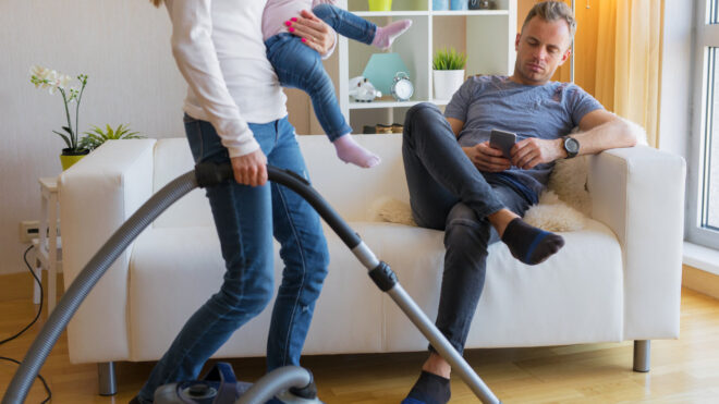Woman cleaning while man sits