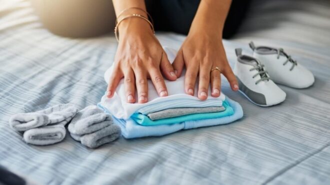 woman folding baby clothes