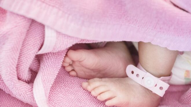 newborn baby girl feet wrapped in a pink blanket