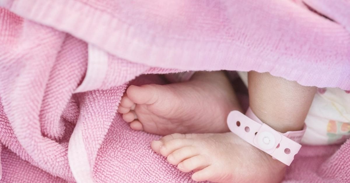 newborn baby girl feet wrapped in a pink blanket