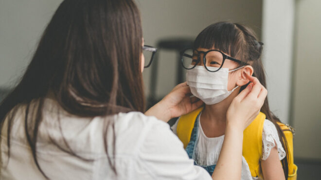 mom putting face mask on daughter heading outside