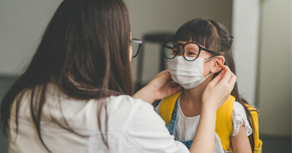 mom putting face mask on daughter heading outside