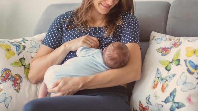 mom breastfeeding baby while sitting on couch