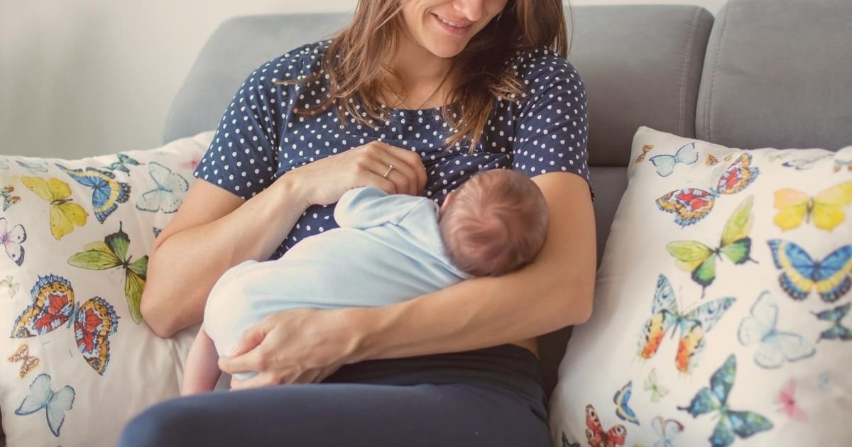 mom breastfeeding baby while sitting on couch