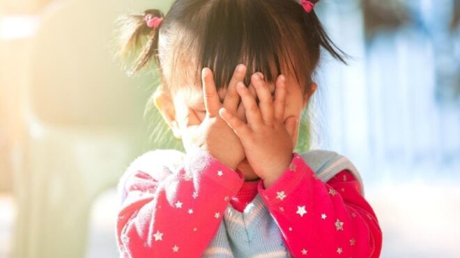 toddler girl covering face with hands