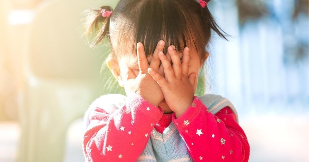 toddler girl covering face with hands