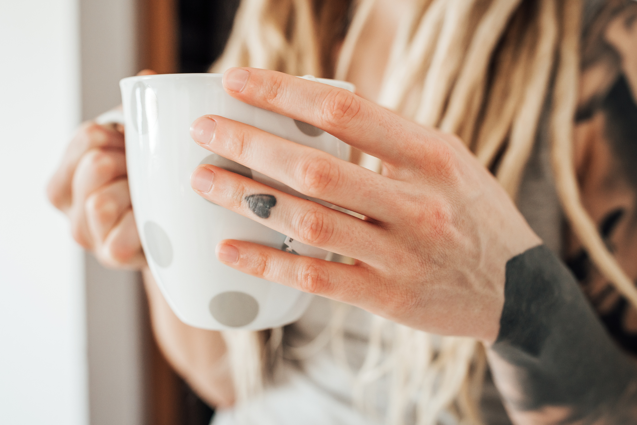 Coffee mug in tattooed woman hands