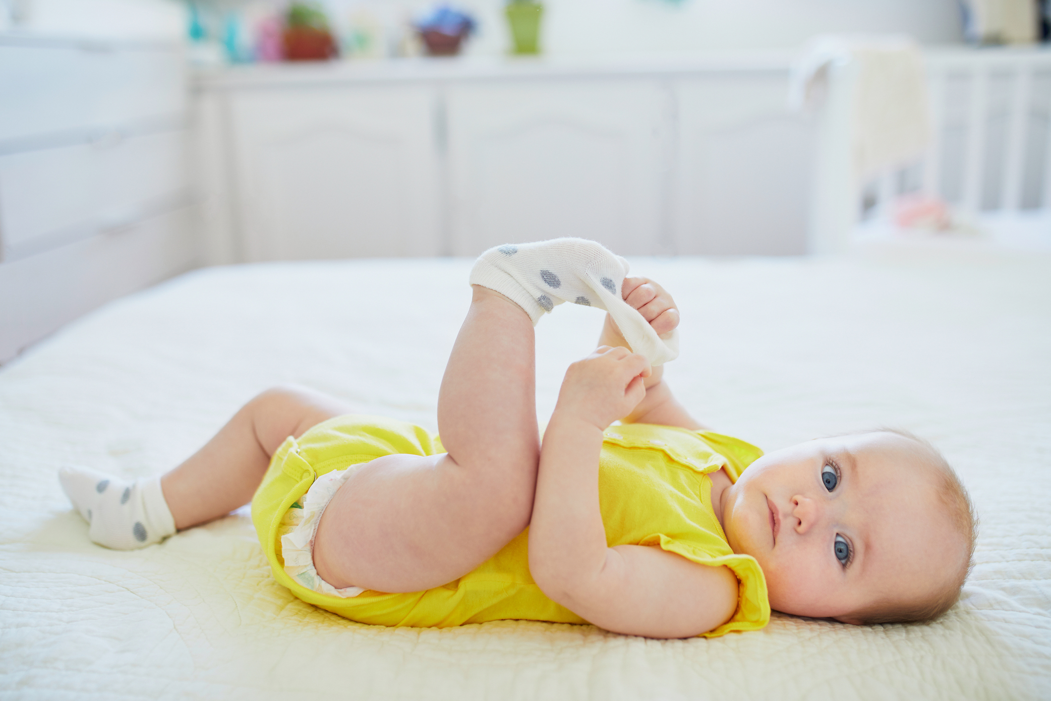 Adorable baby girl removing sock from her foot