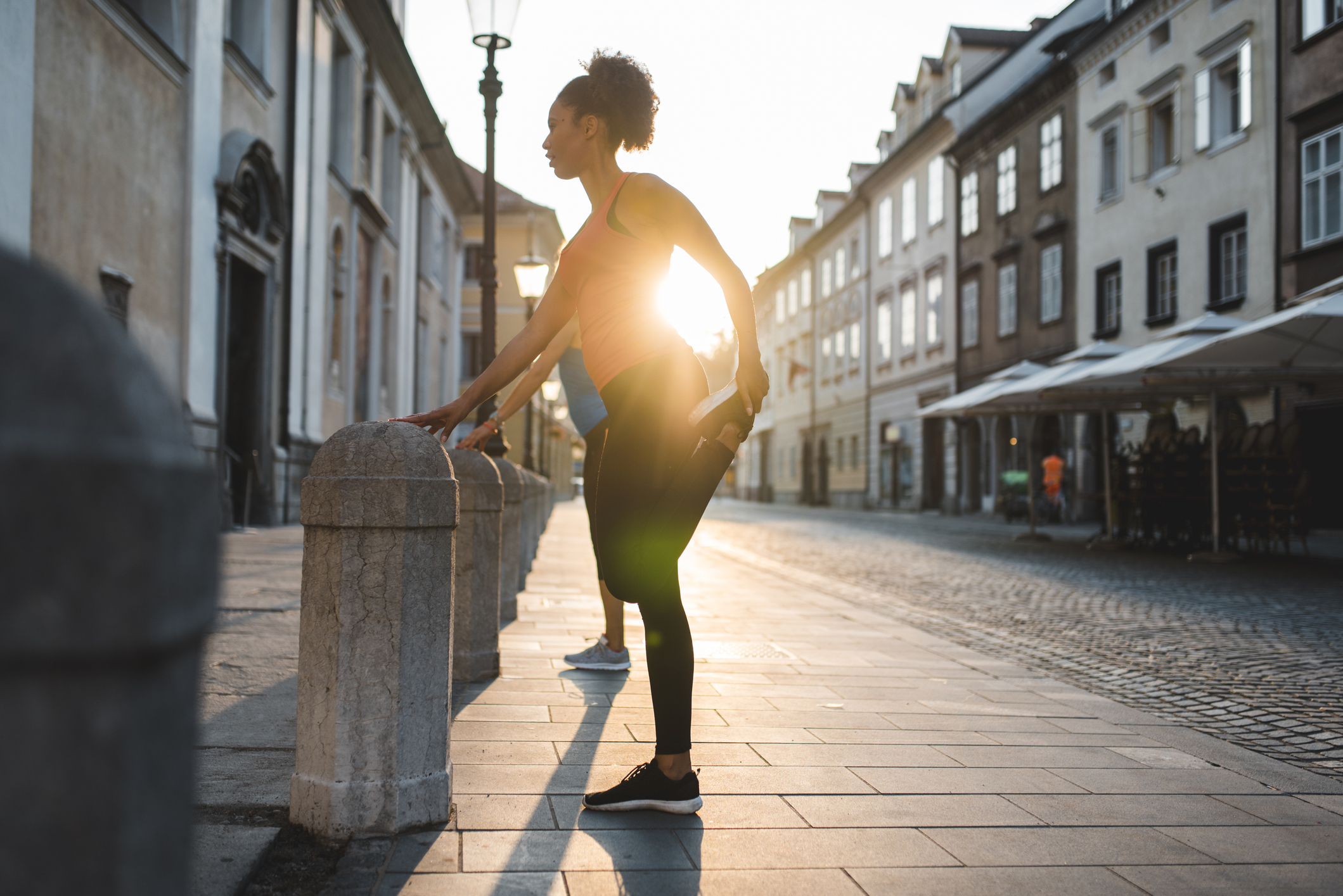 Two women stretching before running in the city