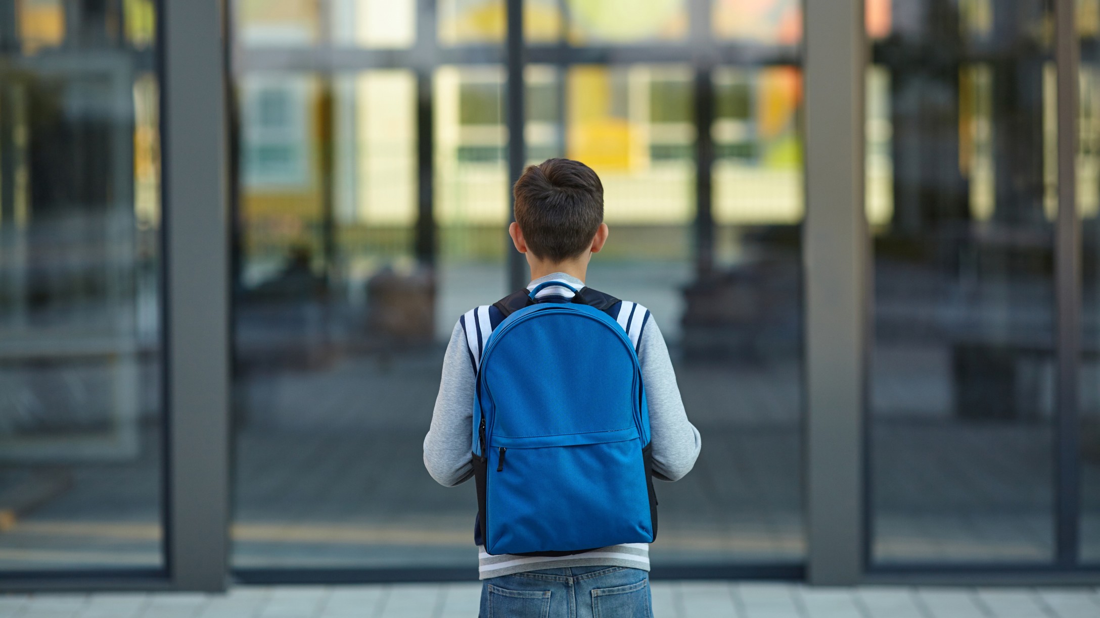 Student with backpack in front of school