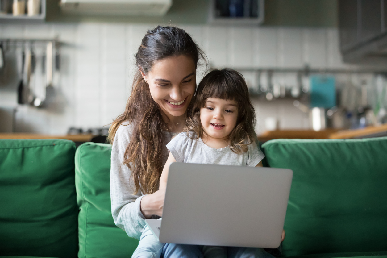 Happy laughing mother and daughter using laptop