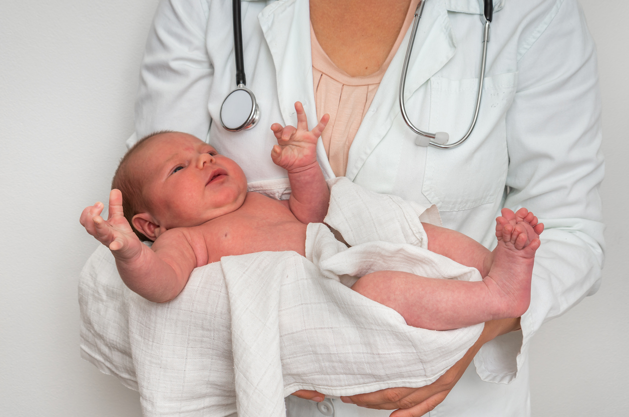Pediatrician doctor is holding newborn baby in arms
