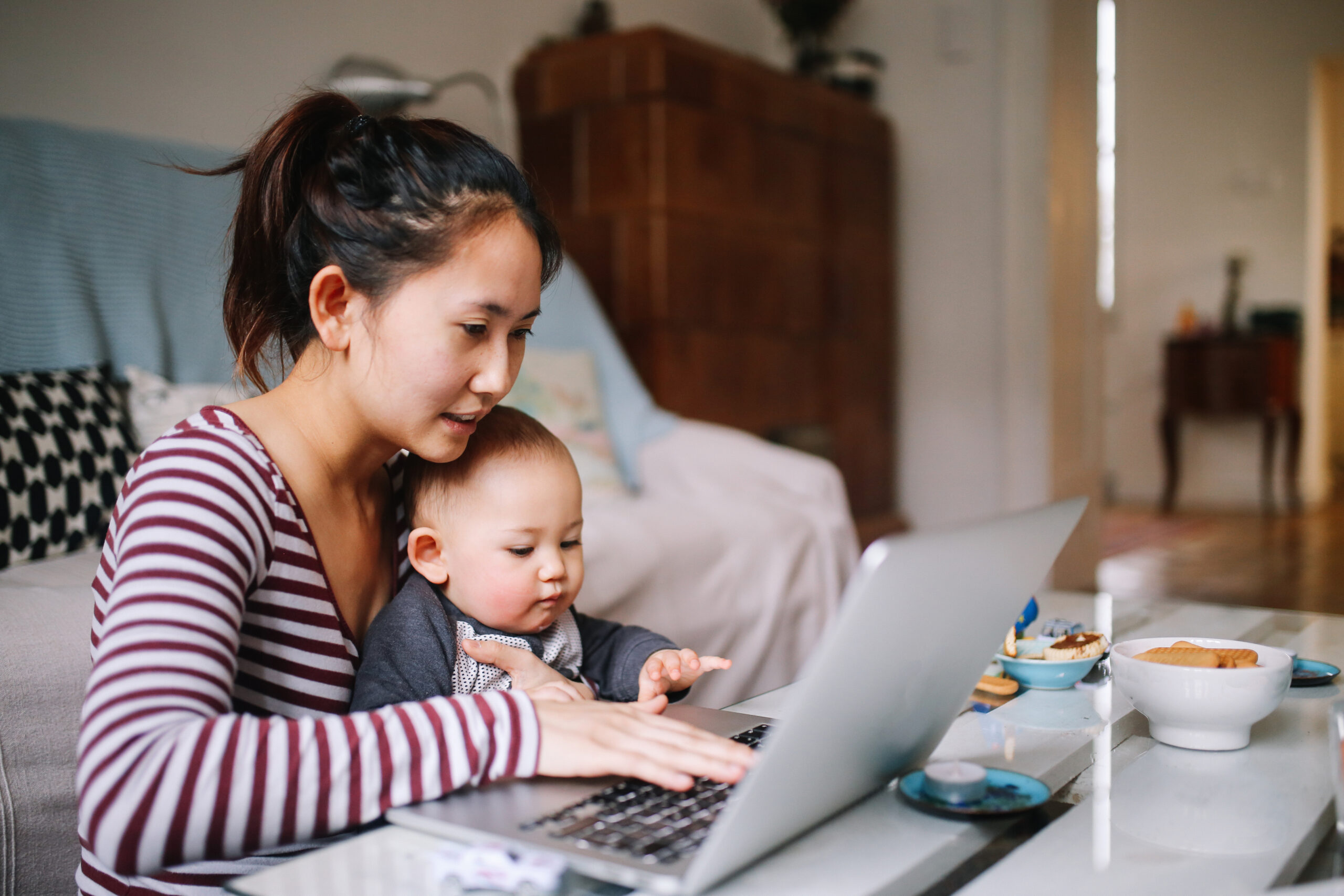 Young Asian mom trying to work with her baby boy