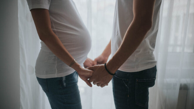 Pregnant woman holding man's hands