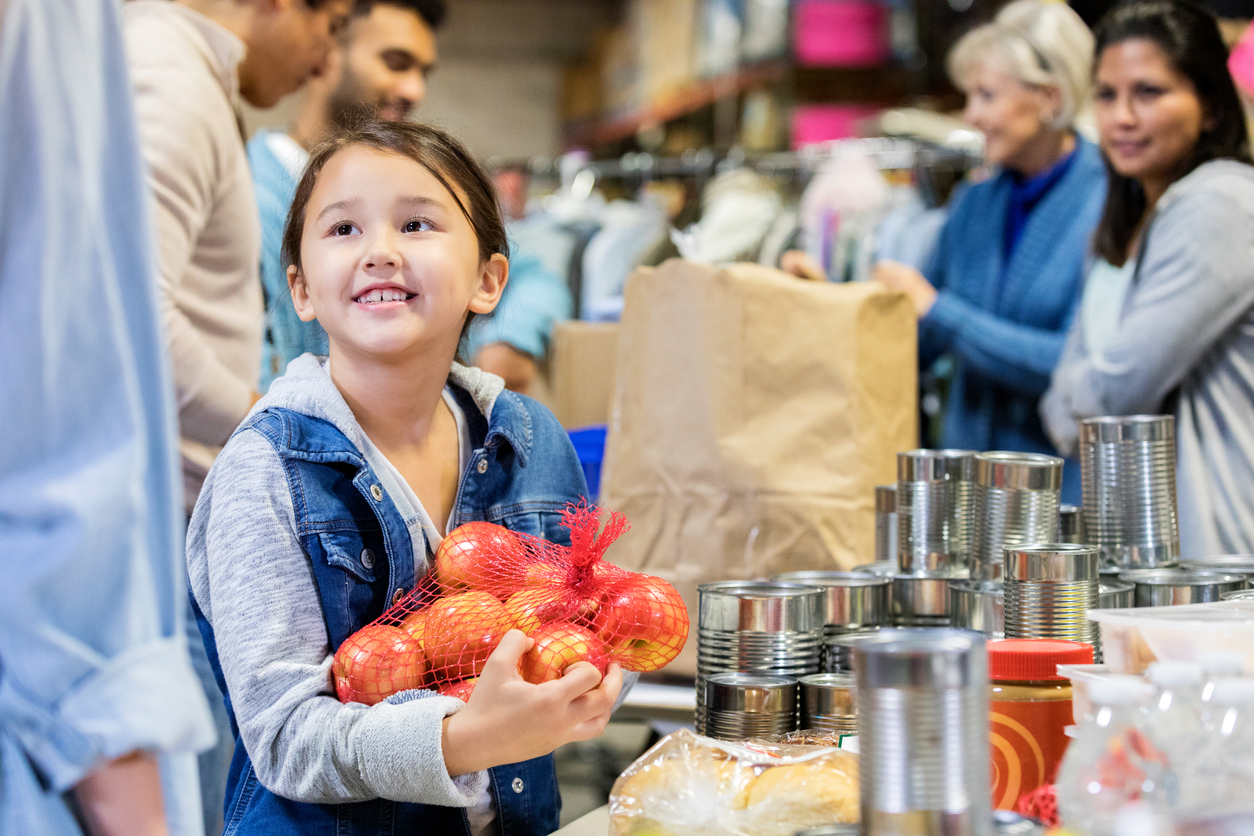 Smiling little girl donates apples to food bank
