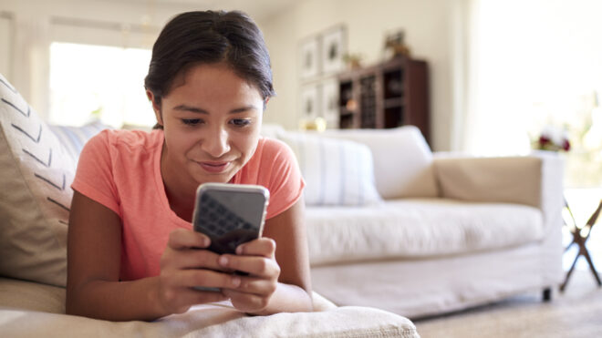 kid on couch looking at smartphone