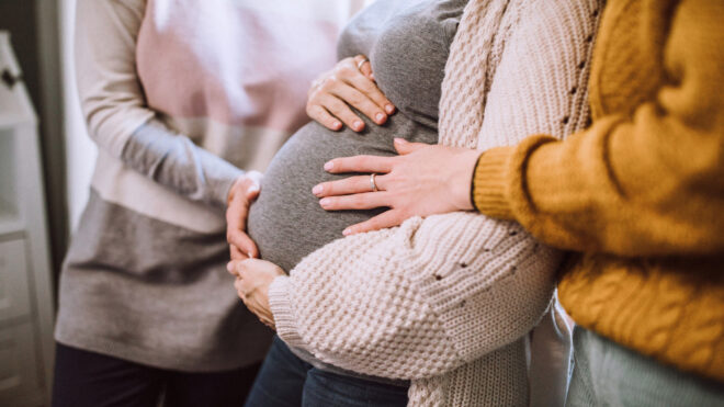 woman touching pregnant woman's belly