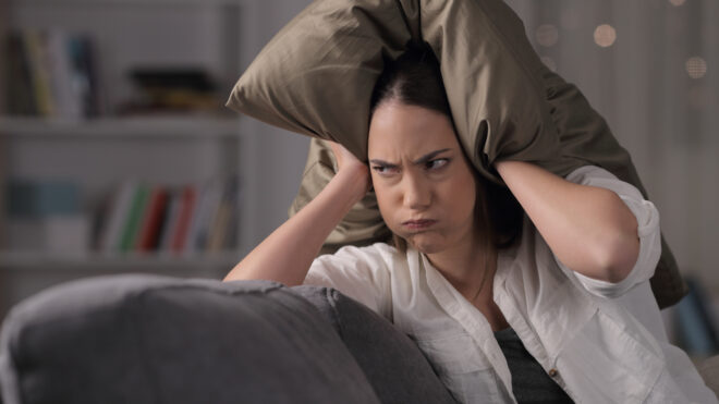 annoyed woman pillow over head