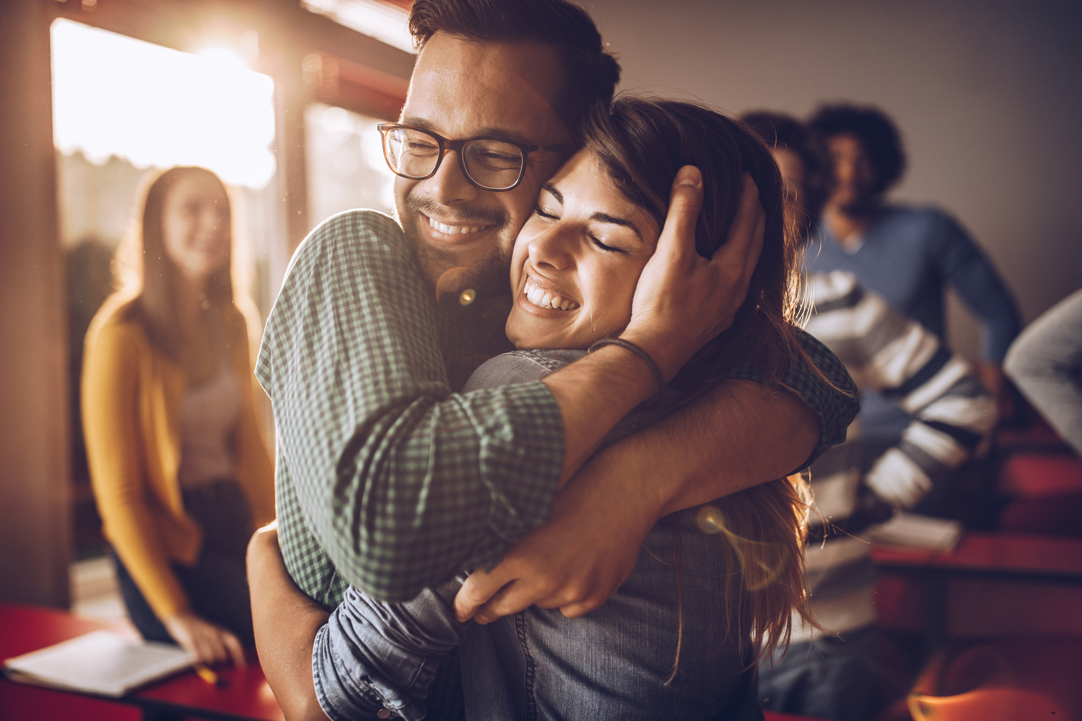 Happy embraced college couple in the classroom.