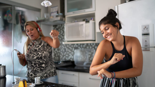 Mom and teen daughter dancing in kitchen