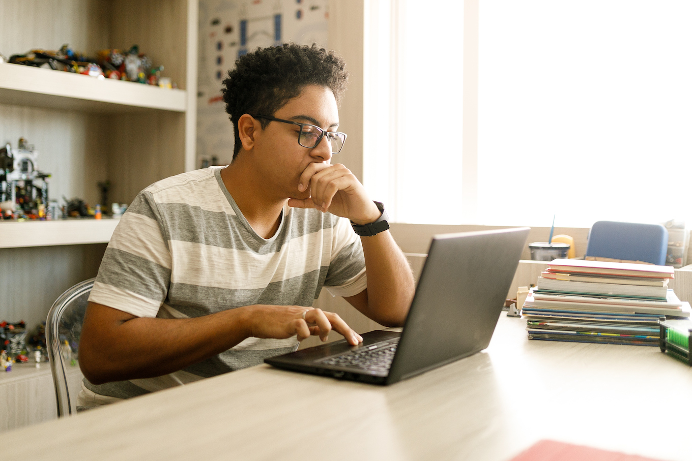 Teenage boy studying with laptop at home