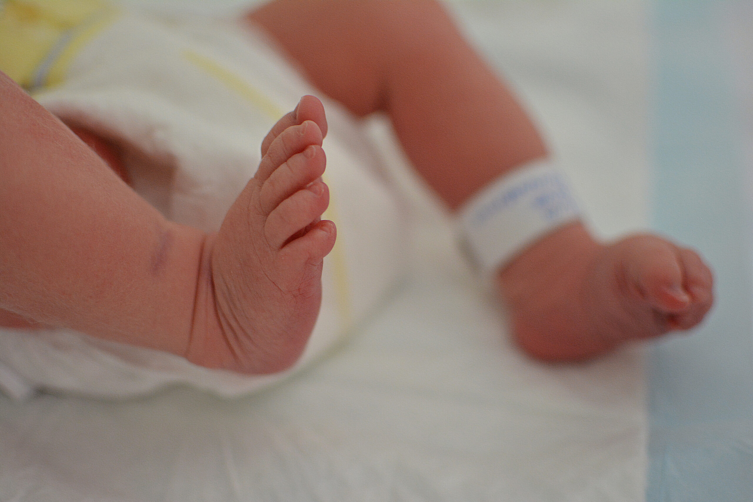 Close-up newborn baby at the hospital with identify tag on feet and diaper.